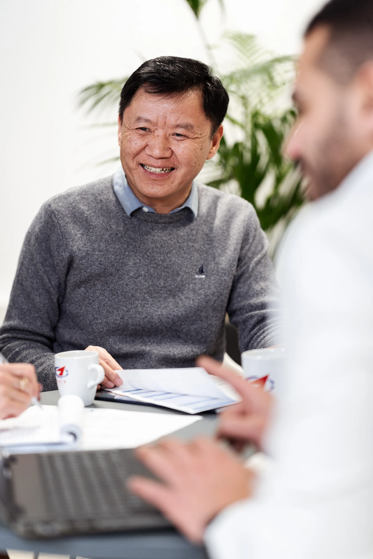 1 smiling man and 1 blurred man sitting and smiling with 1 CC7 Europe cup on the table. 1 smiling man and 1 blurred man sitting and smiling with 1 CC7 Europe cup on the table.