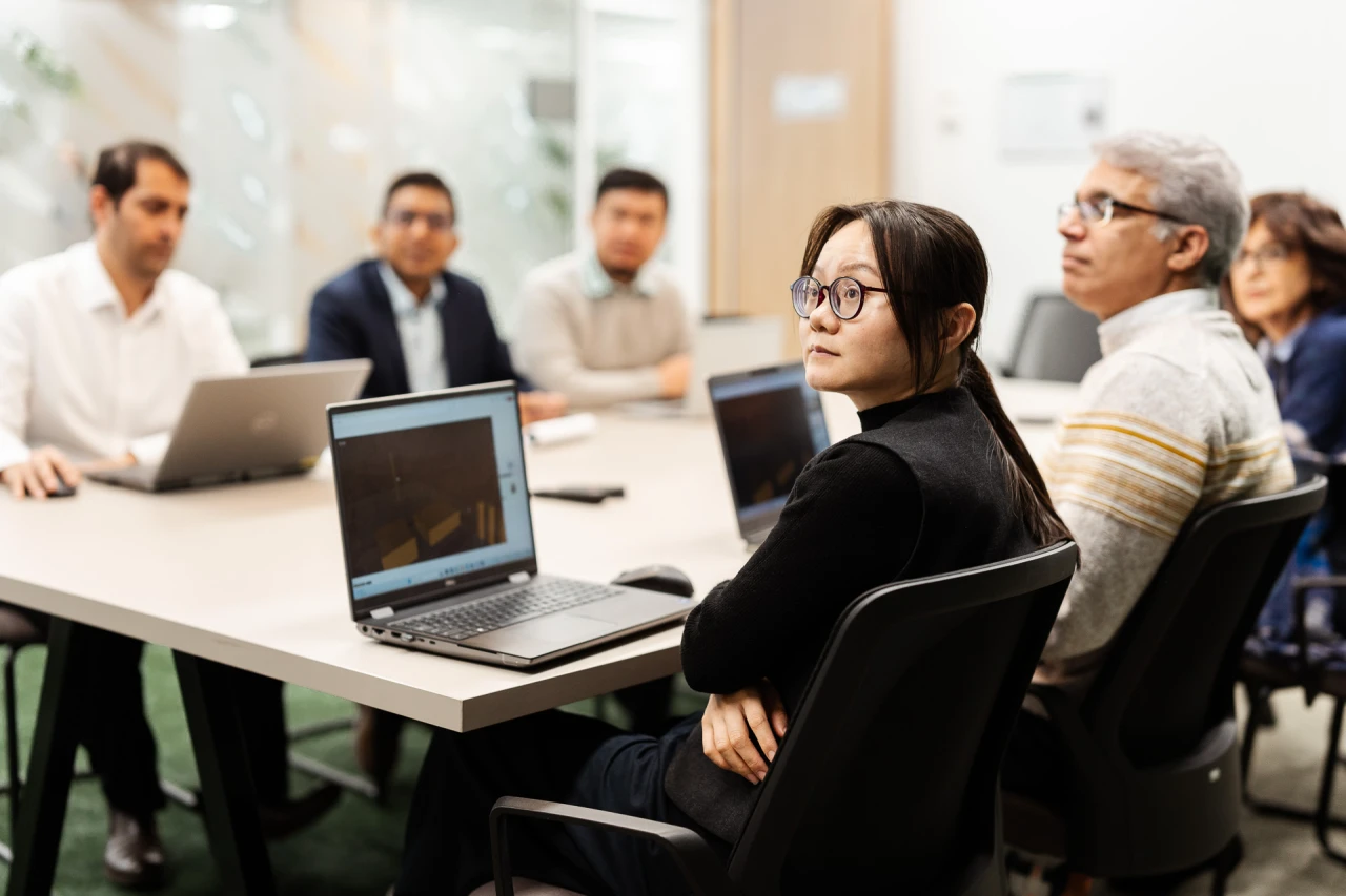 6 people in a meeting room with 3 laptops on the desk.