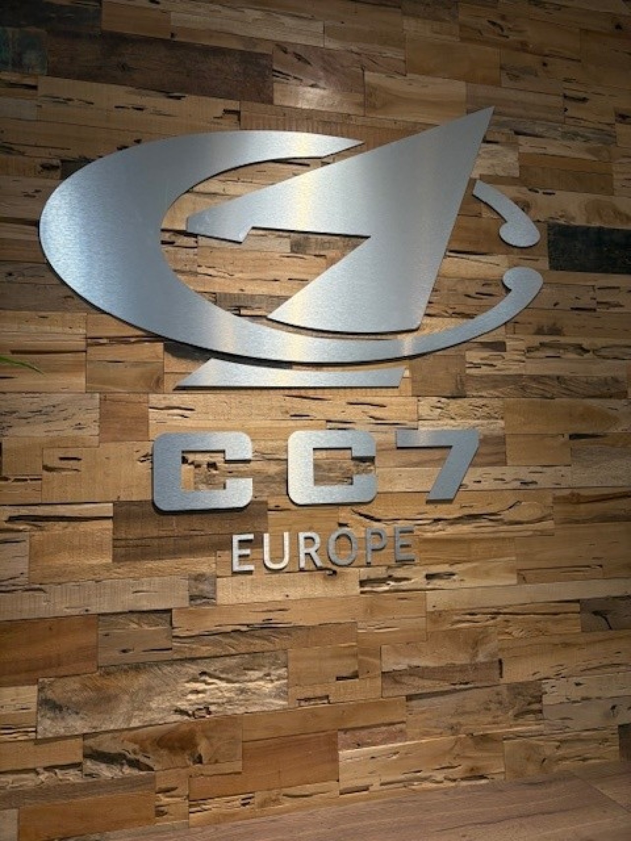 Metal look of the CC7 Europe logo on wooden wall.