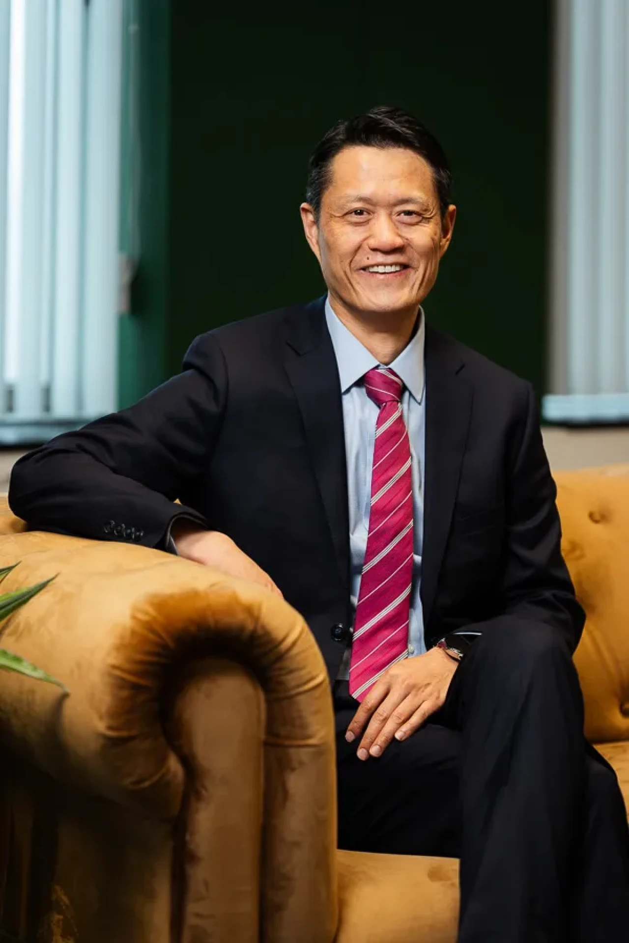 Smart and smiley man sitting on a velvet sofa.